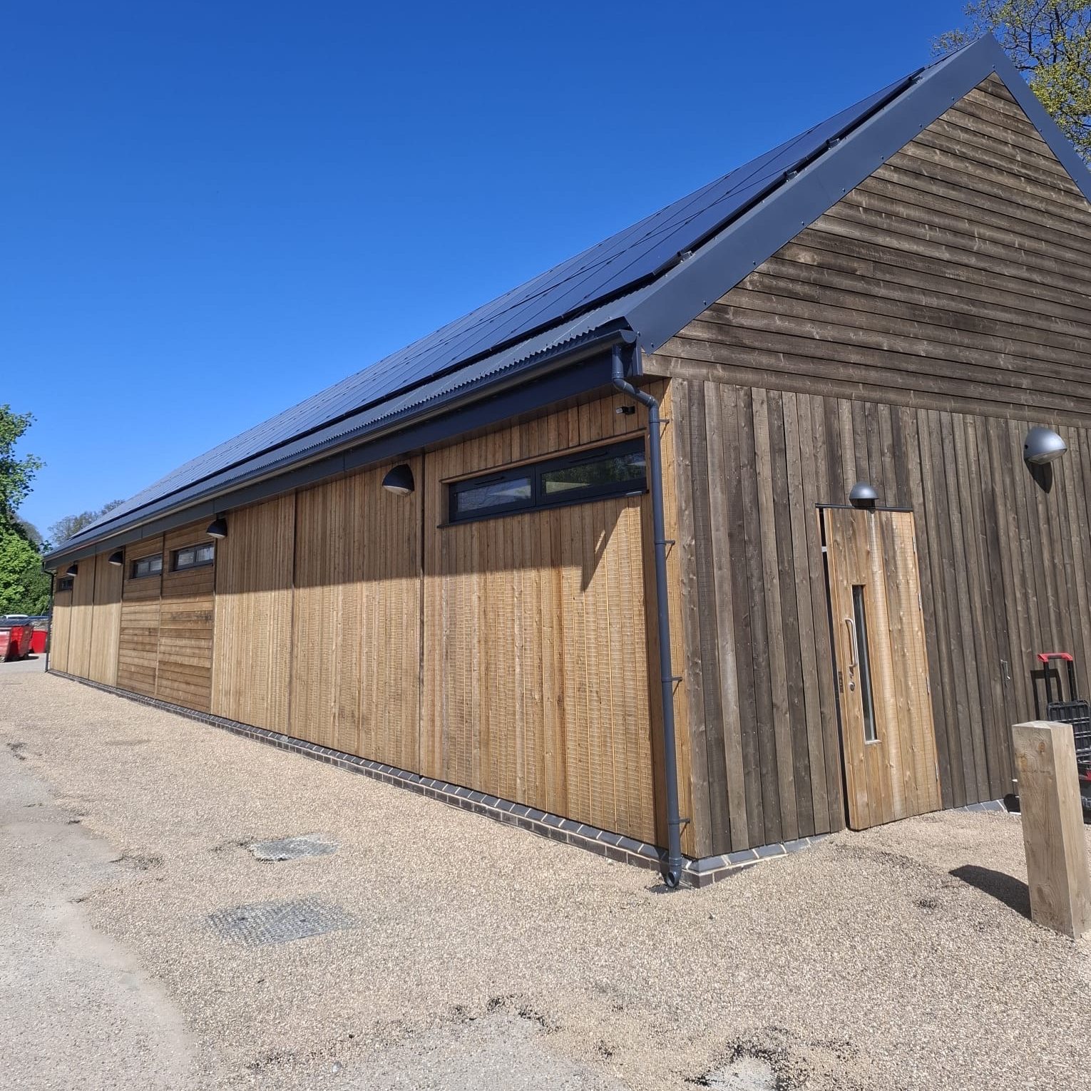 Gable end of the new timber-clad Hub Kitchen at Calke Abbey, with the roof-mounted solar PV array running the length of the building